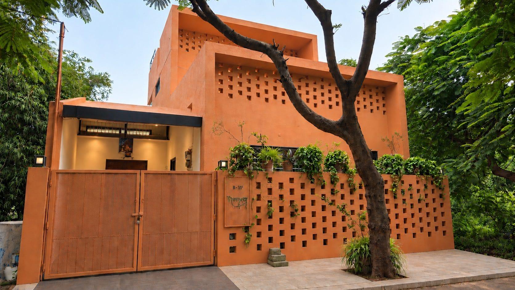 Street front: terracotta walls with a perforated brick screen, framed by trees
